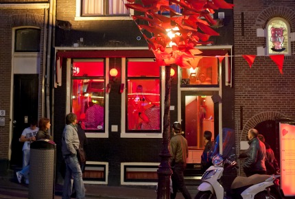 In Amsterdam, prostitutes sway hypnotically in rose-hued windows