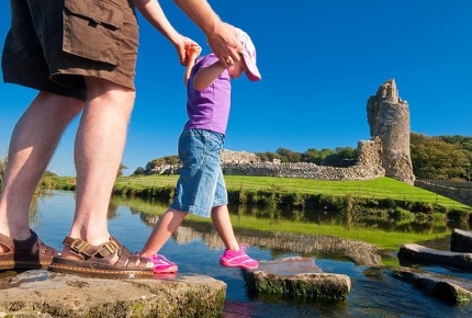 Navigate stepping stones in a river to reach Ogmore Castle