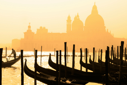 Gondolieri boats bob beneath a Venice sunset